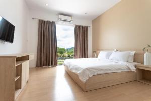 a bedroom with a bed and a large window at O2 Hotel Lopburi in Lop Buri