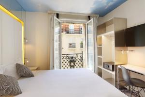 een slaapkamer met een bed, een bureau en een raam bij Nouvel Hôtel Eiffel in Parijs