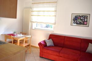 un soggiorno con divano rosso e tavolo di Ferienwohnung Pippohof ad Appiano sulla Strada del Vino