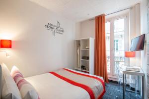 a bedroom with a bed and a tv and a window at Hôtel Amaryllis in Nice
