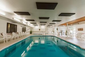 una piscina con sedie e tavoli bianchi in un edificio di EverSpring Suites a Bismarck