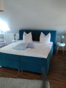 een blauw bed met witte kussens in een kamer bij ostseeurlaub-asmussen in Gelting