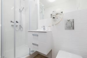 a white bathroom with a shower and a sink at Villa Ula Apartament in Pobierowo +15 photos