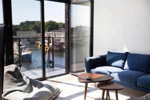 salon z niebieską kanapą i dużym oknem w obiekcie Apartamenty Port Ustka w Ustce