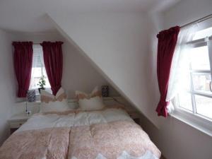 a bedroom with a large bed with red curtains at Haus-Sonnenschein in Tinnum