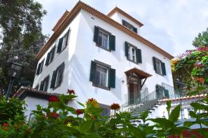 a white building with black windows and flowers at Quinta Da Penha De Franca in Funchal