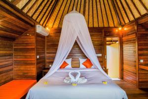 a bedroom with a bed with a mosquito net at Samanta Huts in Nusa Lembongan