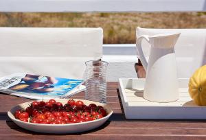 a table with a bowl of cherries and a jug of milk at Mirabeli Apartments & Suites in Pollonia