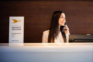 a woman talking on a cell phone in front of a sign at Novotel Budapest Danube in Budapest