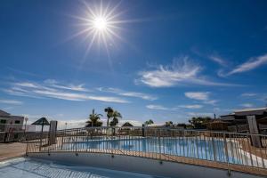 a swimming pool with the sun in the sky at bungalow con gran terraza con vistas in Maspalomas