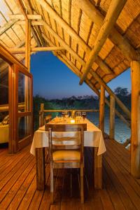 uma mesa de madeira com 2 cadeiras num deque de madeira em Rhino Post Safari Lodge em Skukuza