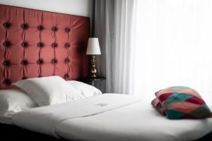 a bedroom with a bed with a red headboard and a window at Hotel Flora in Gothenburg