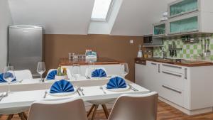 a kitchen with white tables and chairs with blue napkins at Boomerang Apartment Bled in Bled