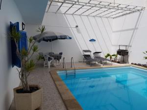 a swimming pool with an umbrella and a table and chairs at Casa Beatriz in Famara