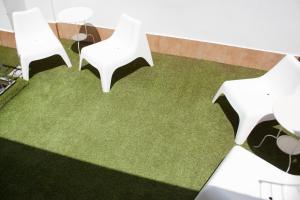 two white chairs sitting on top of a green lawn at Urban Malaga Apartments in Málaga