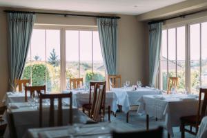 a dining room with white tables and chairs and windows at Sheedy's Hotel in Lisdoonvarna
