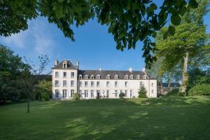 a large white building with a large grass yard at Château du Baffy in Colombiers-sur-Seulles