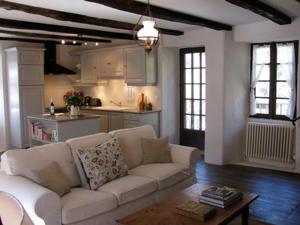 sala de estar con sofá blanco y cocina en L'Ancienne Ecole, en Entraygues-sur-Truyère