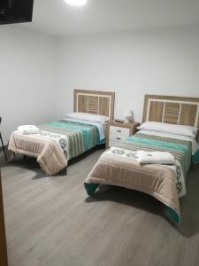 two beds in a room with wooden floors at Pension Diana in O Pedrouzo