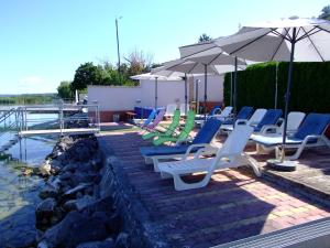 a group of lounge chairs and umbrellas next to a pool at Sunset Beach Apartmanház in Balatonvilágos