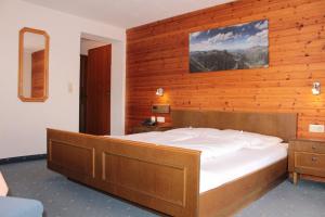 una camera da letto con un letto grande con una parete in legno di Hotel Valisera a Galtür