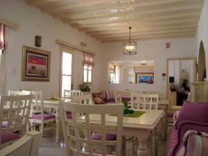 a dining room with white chairs and a table at Magas Hotel in Mýkonos City