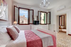 1 dormitorio con 1 cama, TV y ventanas en Accademia opera deluxe en Venecia