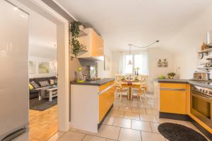 a kitchen with yellow cabinets and a living room at Ferienwohnung Auszeit in Markdorf