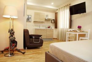 a bedroom with a bed and a chair and a kitchen at Domus Cuseni in Taormina