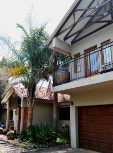 a house with a balcony and a palm tree at At Olive Guesthouse in Vanderbijlpark