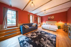 ein Schlafzimmer mit roten Wänden und einem Bett und einem Sofa in der Unterkunft Design Apartments - "Im Holländerhaus" in Potsdam