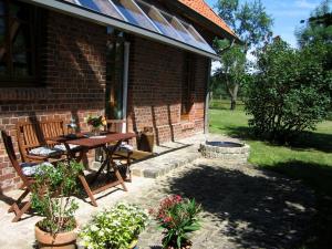 patio ze stołem i krzesłami obok ceglanego domu w obiekcie Fewos in Klein-Grindau w mieście Schwarmstedt