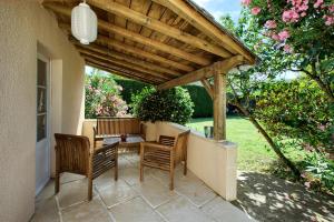 a patio with two chairs and a wooden pergola at Les Abris de Saint Sulpice - Saint-Émilion in Saint-Sulpice-de-Faleyrens