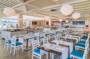 a restaurant with white tables and blue chairs at H10 Suites Lanzarote Gardens in Costa Teguise