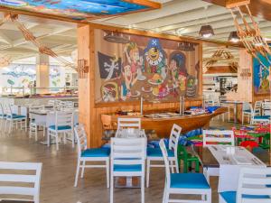 a restaurant with white tables and chairs and a mural at H10 Suites Lanzarote Gardens in Costa Teguise