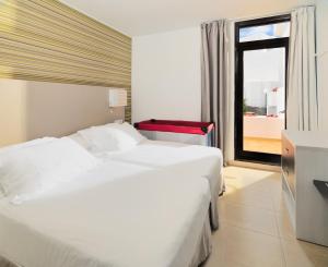 a hotel room with two beds and a window at H10 Suites Lanzarote Gardens in Costa Teguise