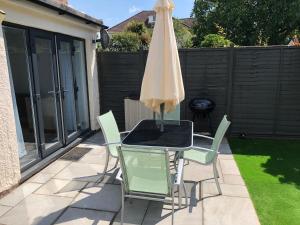 a table and chairs with an umbrella on a patio at Bournemouth Hot Tub & Sauna Holiday Let in Bournemouth