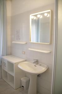 a white bathroom with a sink and a mirror at VIA DELLA SOGLIOLA in Marina di Castagneto Carducci