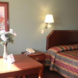 a hotel room with a bed and a table with a phone at Executive Inn & Suites - Covington in Covington