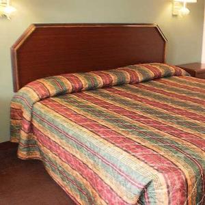 a bed in a hotel room with a colorful bedspread at Executive Inn & Suites - Covington in Covington