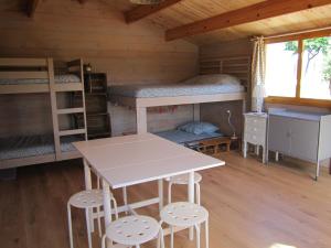 a room with bunk beds and a table and stools at La Grange de Campaulise - Camping à la ferme - Hébergements - Mont Ventoux in Mazan
