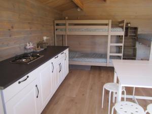 a kitchen with white cabinets and a bunk bed at La Grange de Campaulise - Camping à la ferme - Hébergements - Mont Ventoux in Mazan