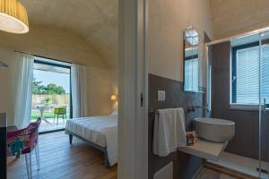 a bedroom with a bed and a bathroom with a sink at Casale Ramunno in Ostuni