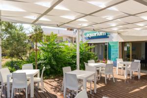 a patio with white tables and chairs under a white umbrella at AquariumResidence in San Pietro in Bevagna