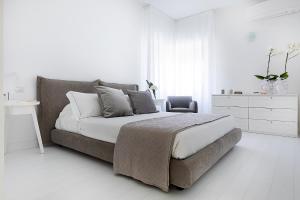 a white bedroom with a bed and a chair at White Stylish Apartments 2 in Vico Equense