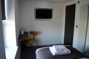 um quarto de hotel com uma cama e uma cadeira e uma televisão em Q8 Boutique Hotel em Portsmouth