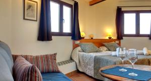 Cortijo Algabia في Alhendín: غرفة نوم بسريرين وطاولة مع كؤوس للنبيذ