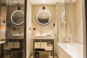 La salle de bains est pourvue de deux miroirs, d'un lavabo et d'une douche. dans l'établissement Mercure Paris 17 Batignolles, à Paris