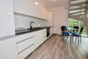 a kitchen with white cabinets and a table with chairs at Apartamenty Amon z widokiem na morze in Darlowko