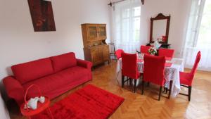 a living room with a red couch and a table with red chairs at APARTMENT PALAZZO ŠARE in Vrbnik
